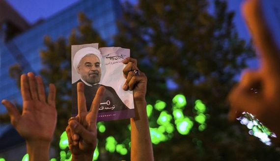 Supporters of moderate cleric Hassan Rouhani hold a picture of him as they celebrate his victory in Iran's presidential election on a pedestrian bridge in Tehran, June 2013